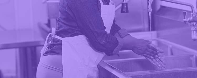 staff member washing their hands at a sink in a purple overlay
